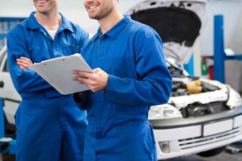 Smiling mechanic working together on clipboard at the repair garage - MOT, Servicing & Repairs | Huntingdon